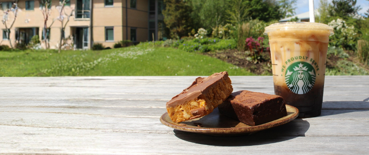 Starbucks iced coffee, brownie and flapjack on a table in the sunshine